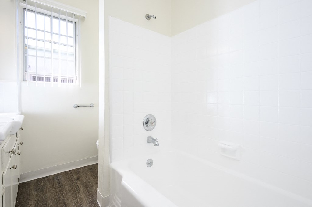 a white bathroom with a tub and a window