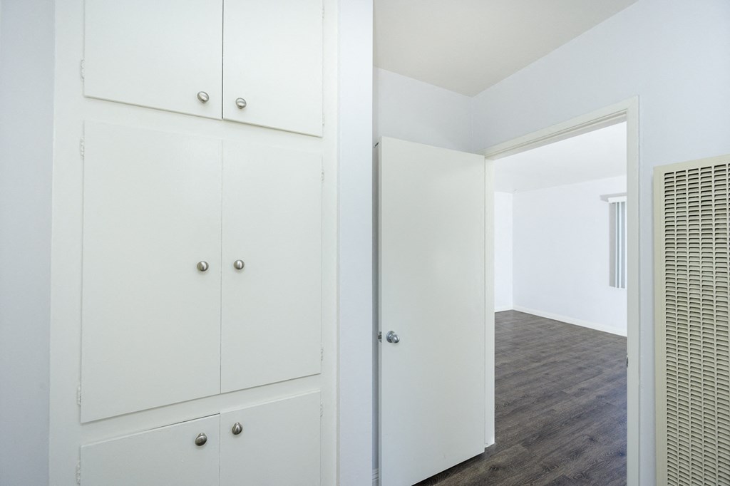 a bedroom with white cabinets and a door to a closet
