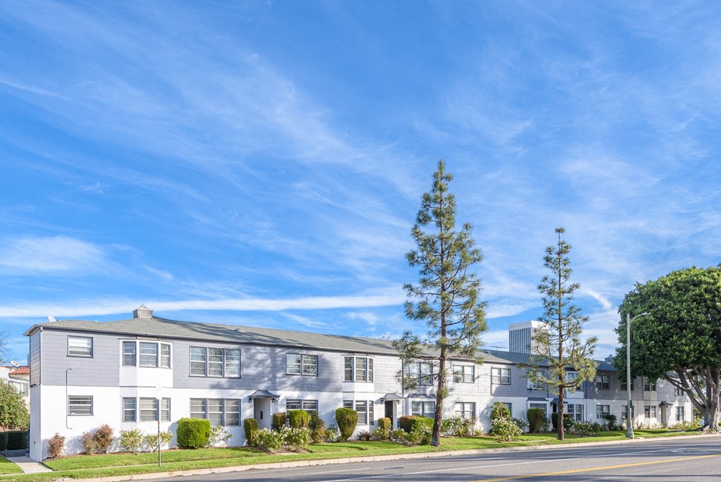 an apartment building on the corner of a street with a blue sky