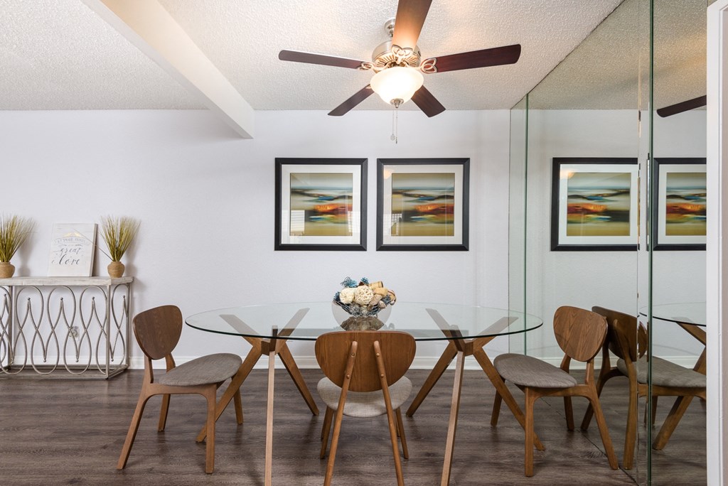 a dining room with a glass table and chairs and a ceiling fan