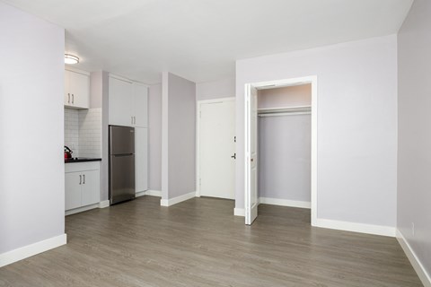 an empty living room with white walls and a stainless steel refrigerator