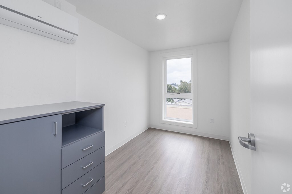 A room with a grey filing cabinet and a window overlooking a parking lot.