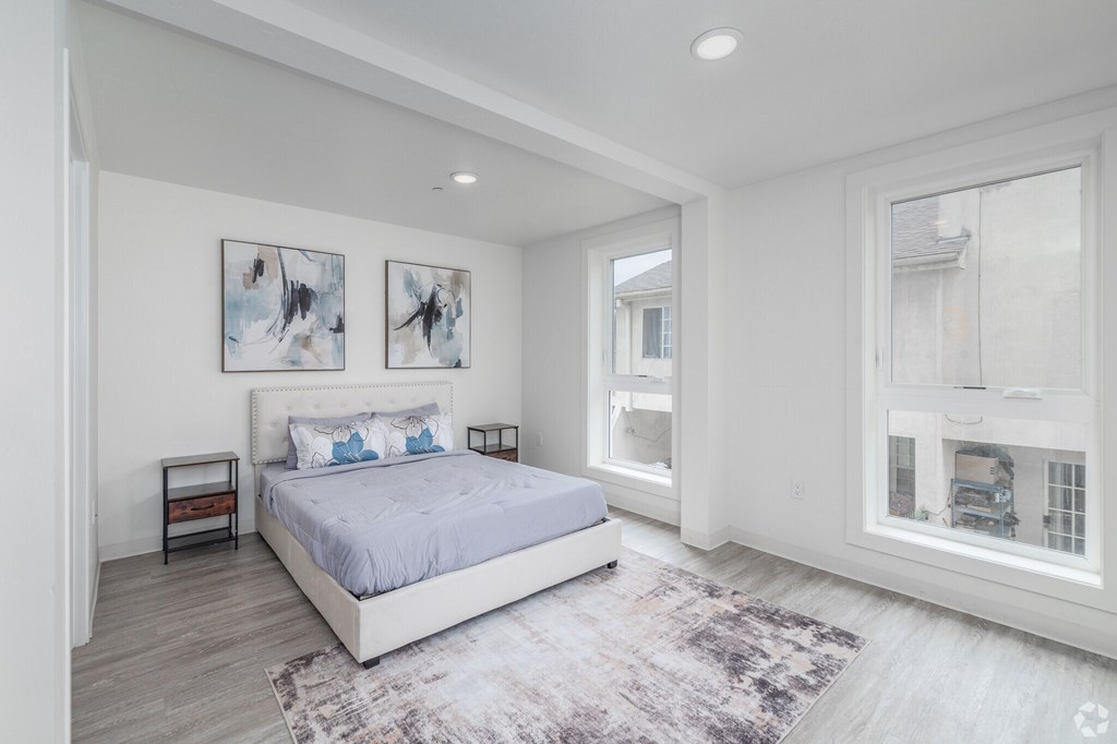 A bedroom with a large bed and two pictures on the wall.