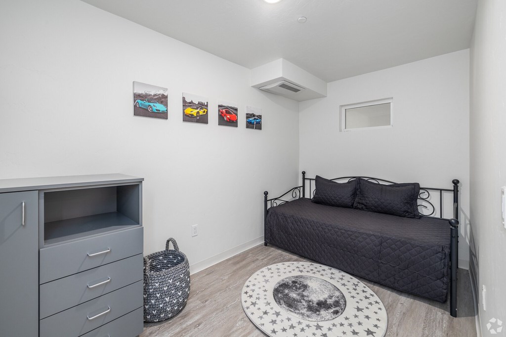 A bedroom with a bed, dresser, and pictures on the wall.