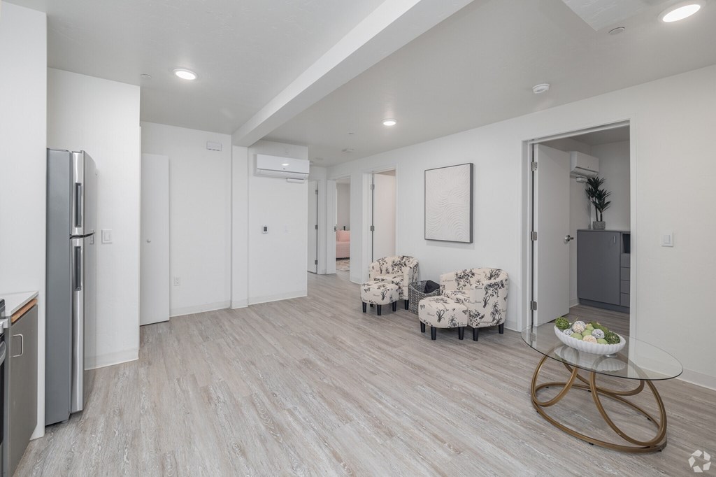A modern kitchen with a refrigerator, a dining table with chairs, and a plant in a pot.
