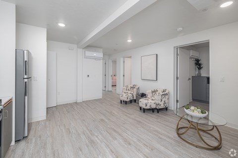 A modern kitchen with a refrigerator, a dining table with chairs, and a plant in a pot.