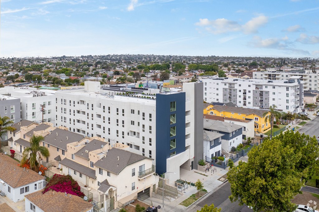 A modern building with a blue accent wall is surrounded by other buildings and houses.