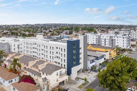 A modern building with a blue accent wall is surrounded by other buildings and houses.