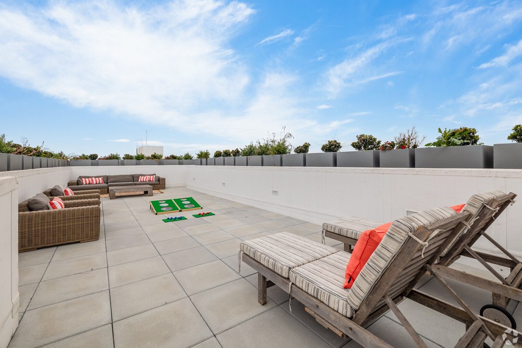 A patio with a white table and chairs and a green rug.