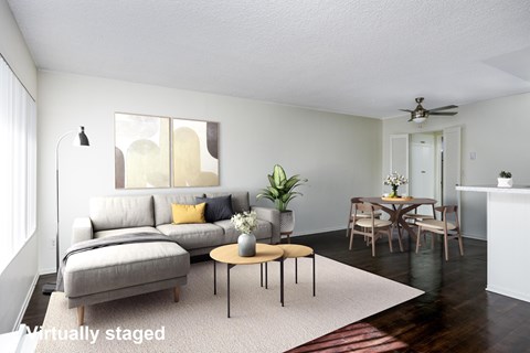 A living room with a grey couch, a coffee table, and a dining table set up.