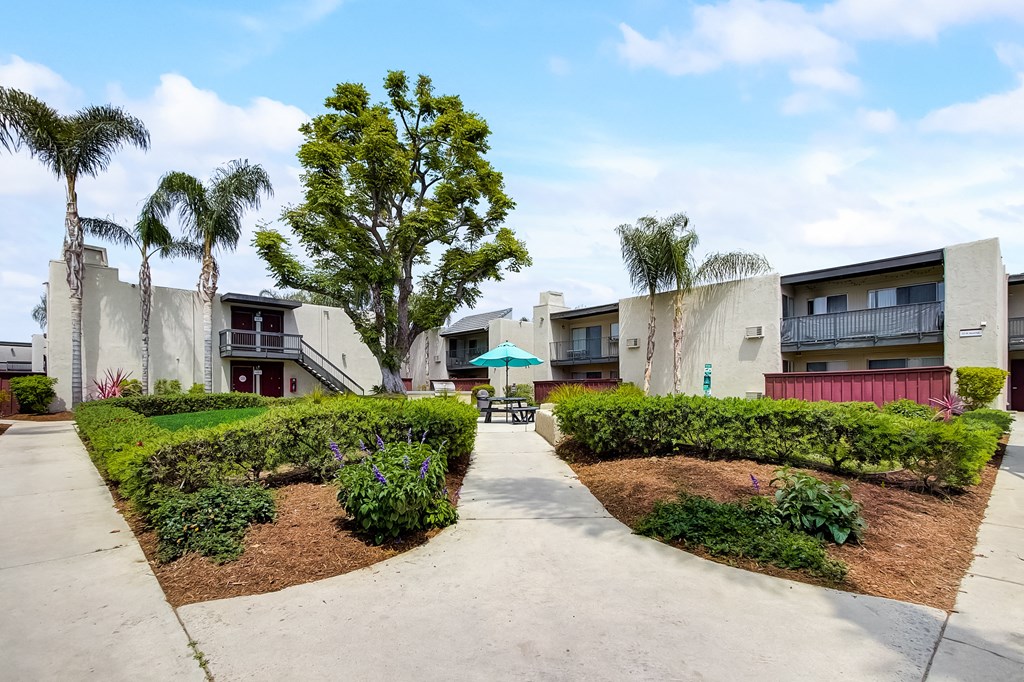 an umbrella sits in the middle of a garden at the whispering winds apartments in pearland,