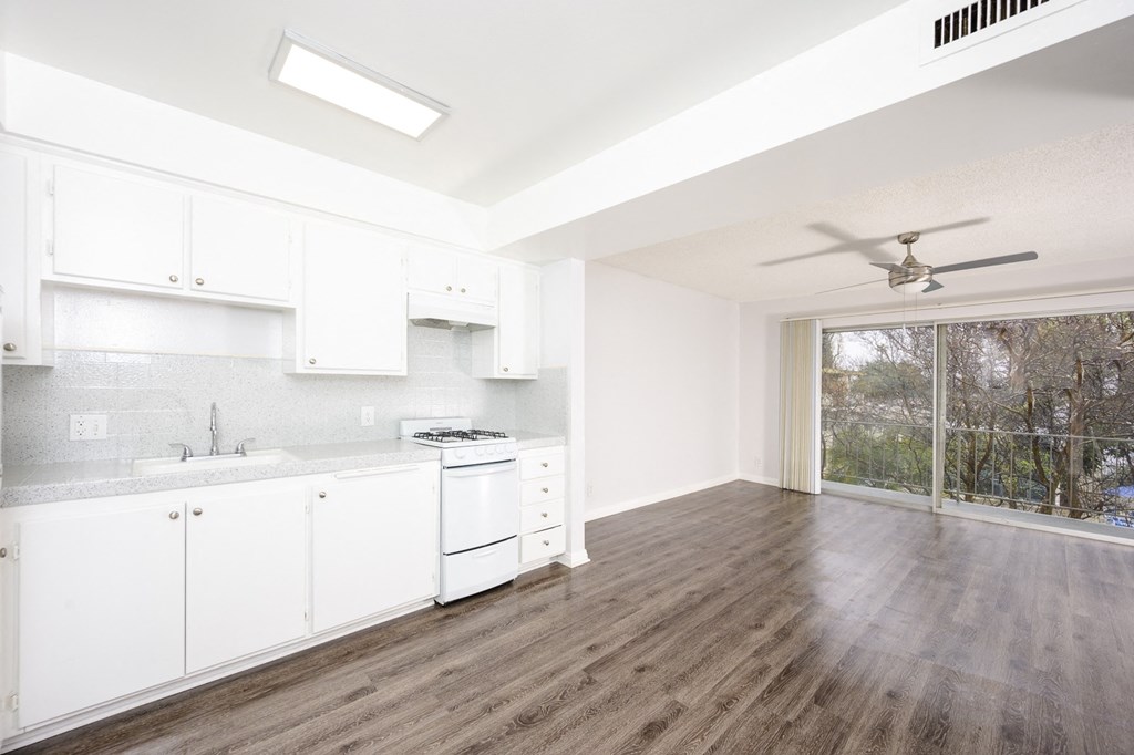 an empty kitchen with white cabinets and a ceiling fan