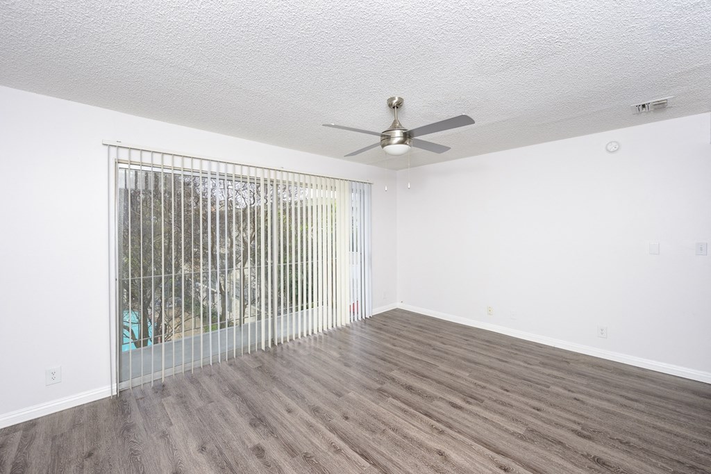 an empty living room with a ceiling fan and a window