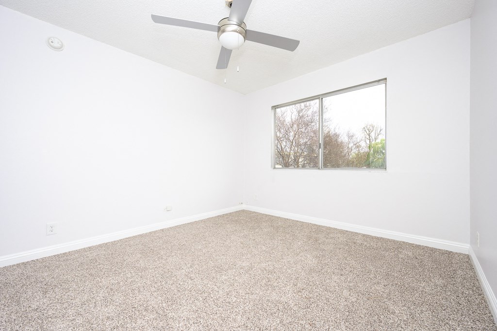 an empty room with a ceiling fan and a window