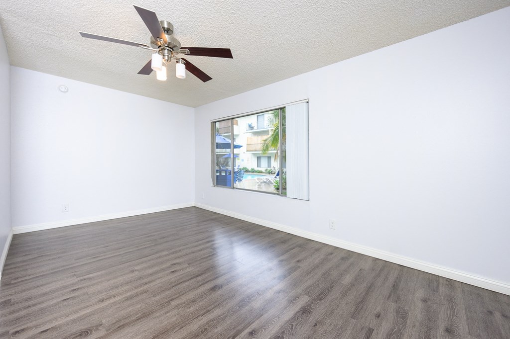 an empty living room with white walls and a ceiling fan