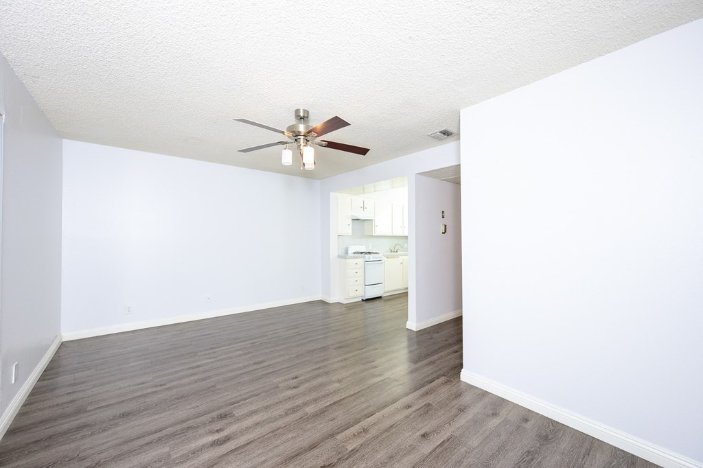 an empty living room with white walls and a ceiling fan