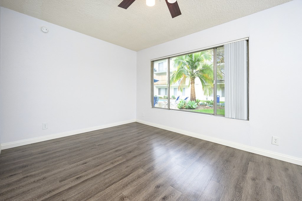 an empty living room with wood floors and a large window
