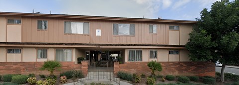 the front of a brown building with a porch and a staircase