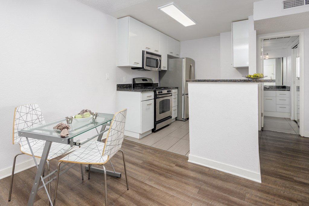 an open kitchen and dining room with a glass table and chairs