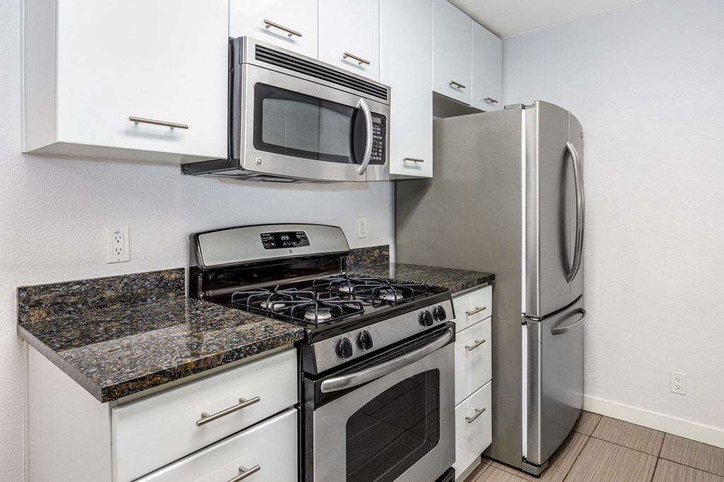a kitchen with white cabinets and stainless steel appliances and a refrigerator