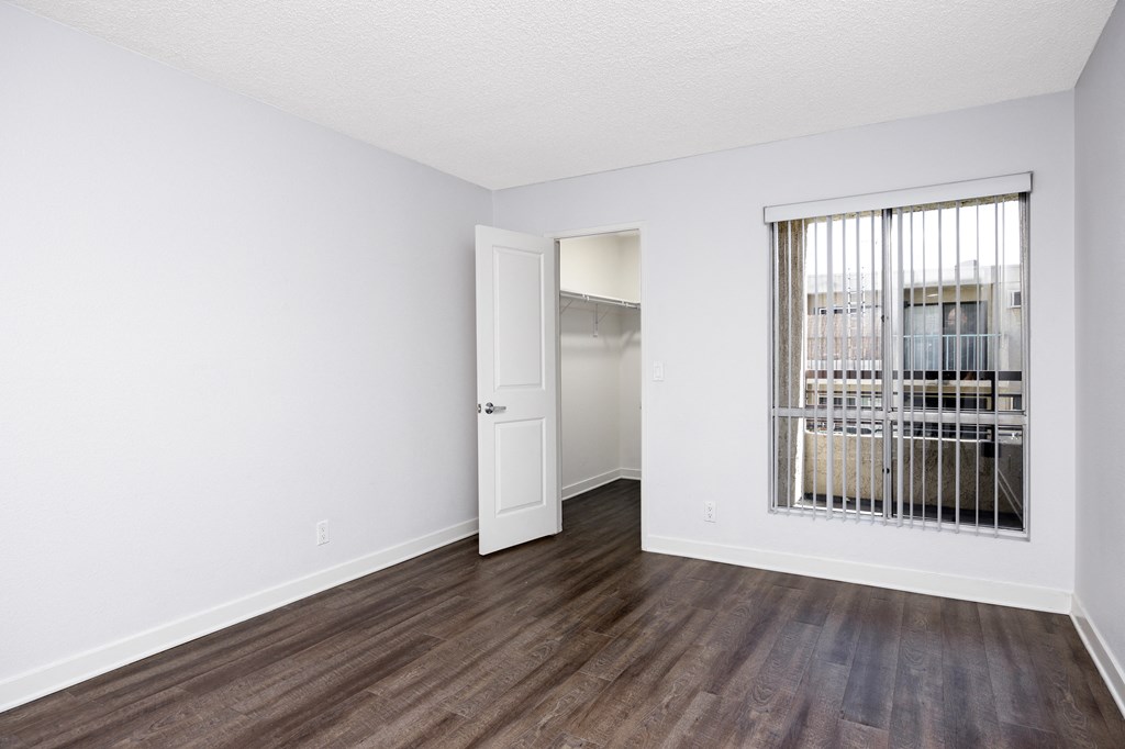 an empty living room with wood flooring and a window