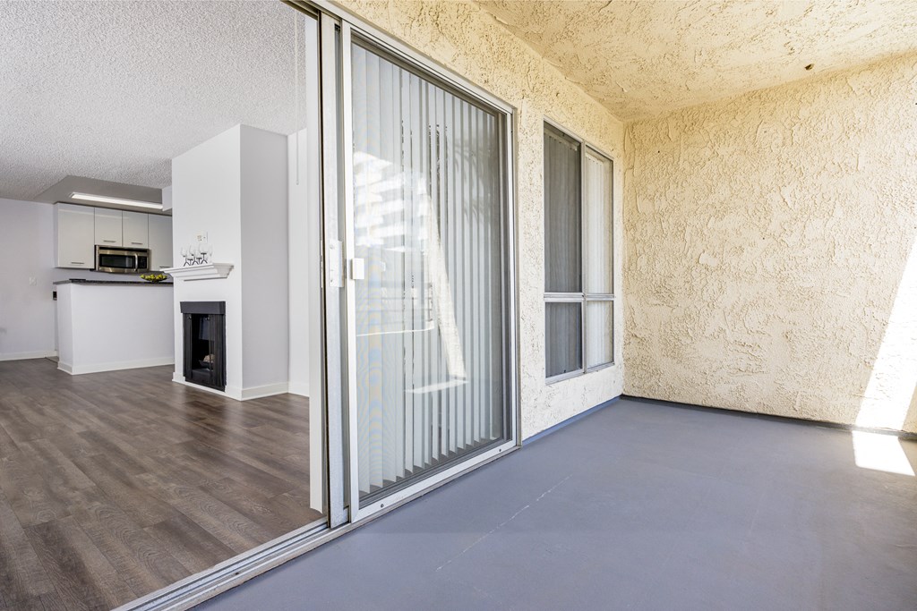 an empty living room with a sliding glass door to a kitchen