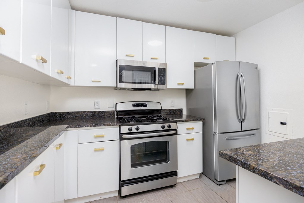 a kitchen with white cabinets and stainless steel appliances