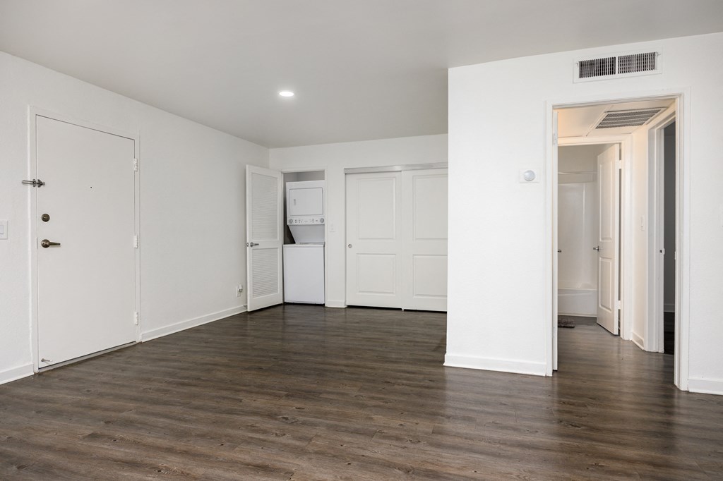 an empty living room with white walls and a wood floor