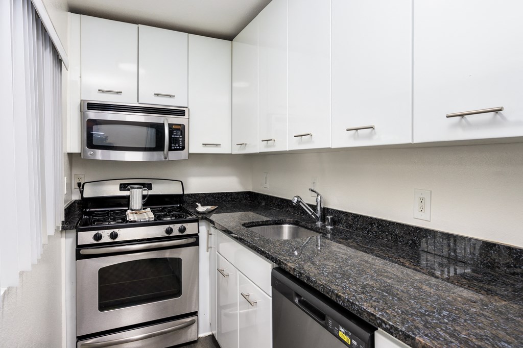 a kitchen with white cabinets and granite counter tops and stainless steel appliances