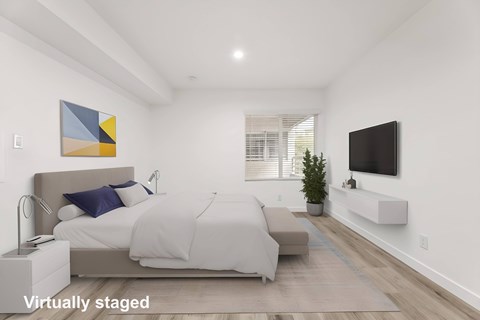 A bedroom with a bed, a couch, a television, and a painting on the wall.