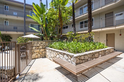 a stone retaining wall with a wooden bench in front of an apartment building