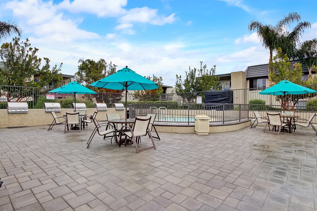 a patio with tables chairs and umbrellas