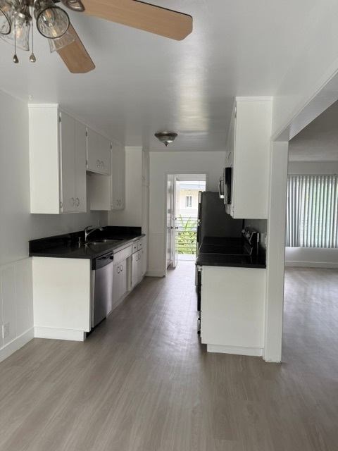 A kitchen with white cabinets and black countertops.