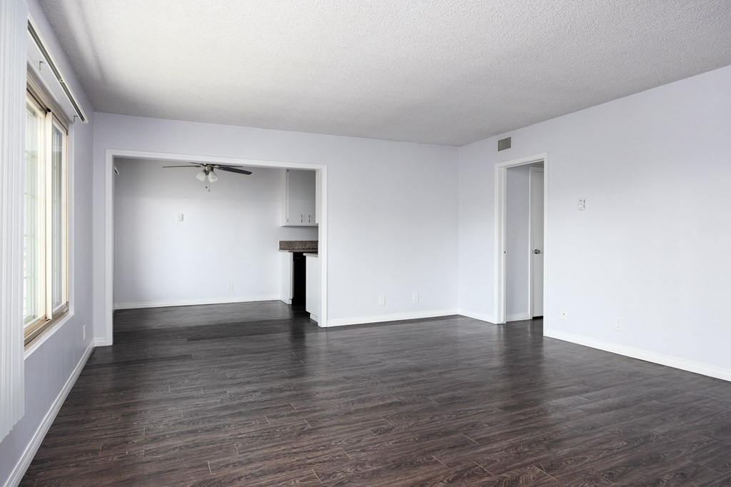 an empty living room with white walls and wood floors