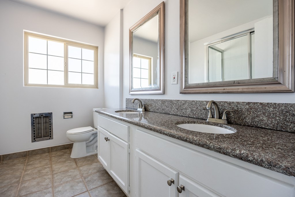 a bathroom with a sink and a toilet and two mirrors