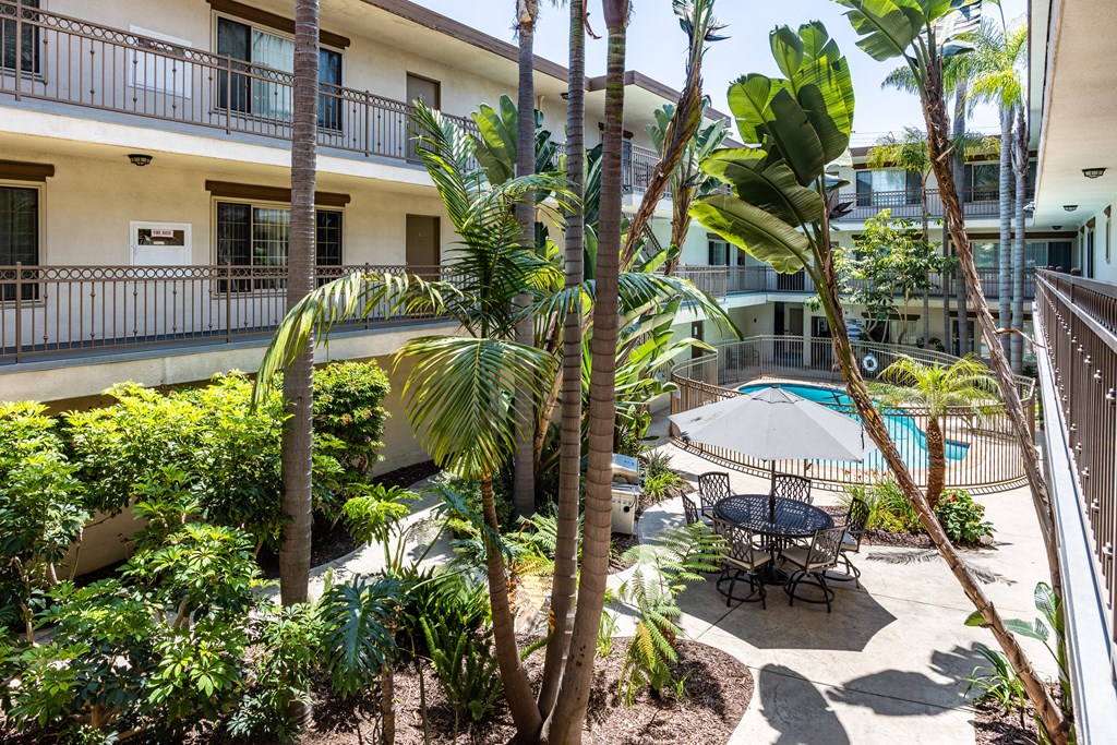 a patio with palm trees and a table and chairs