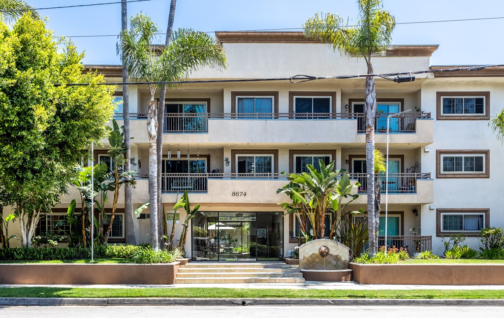 an apartment building with palm trees in front of it