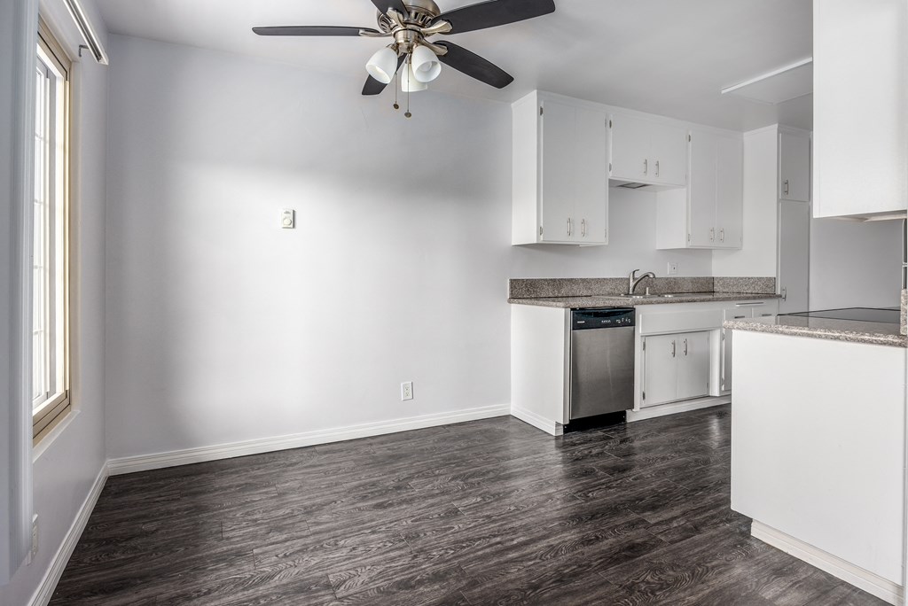 an empty kitchen with white cabinets and a ceiling fan