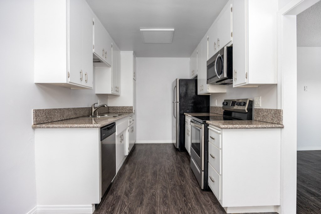 an empty kitchen with white cabinets and stainless steel appliances