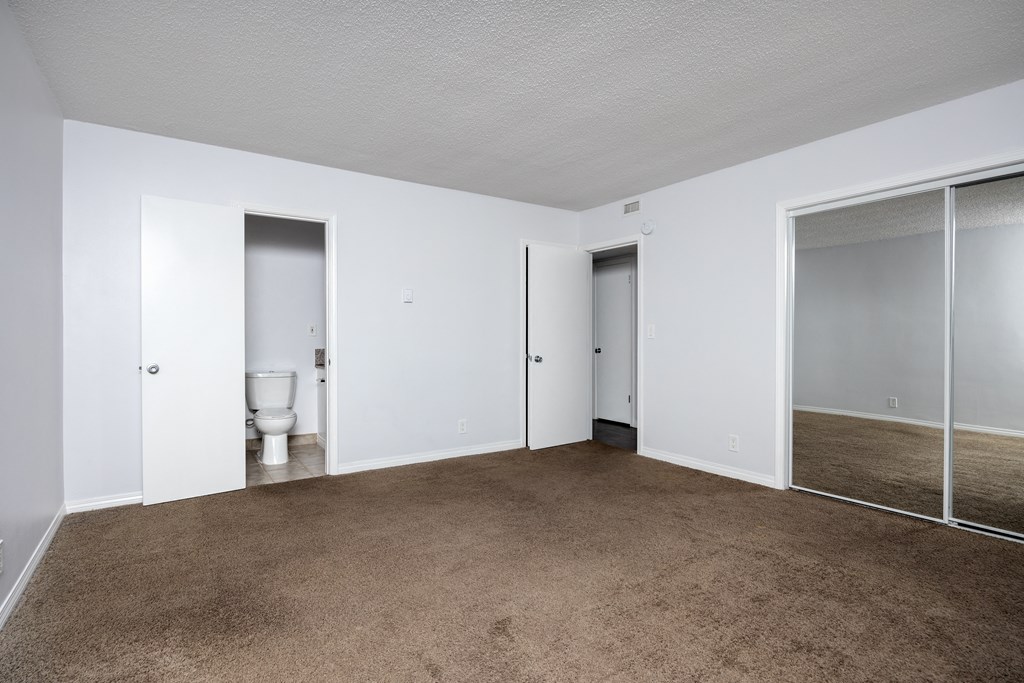 an empty living room with a toilet and sliding glass doors