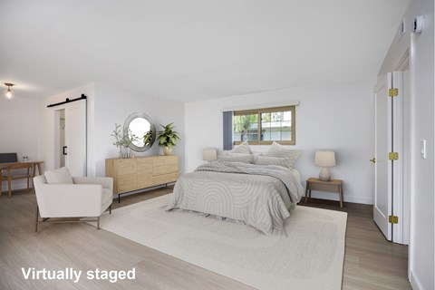 A bedroom with a bed, nightstand, chair, and a window.