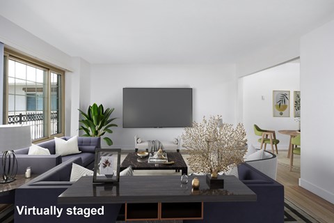 A modern living room with a dark coffee table and a large screen on the wall.