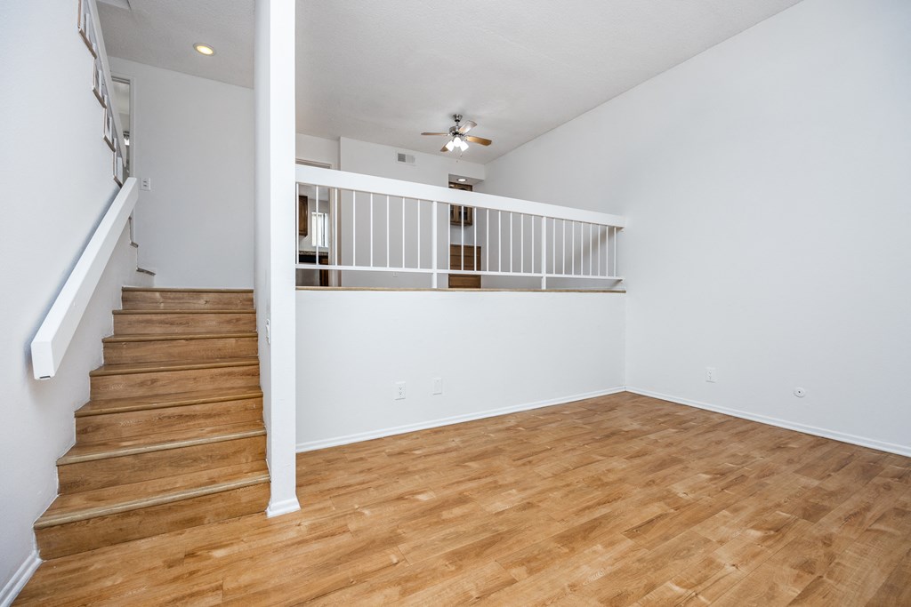 an empty living room with a hard wood floor and stairs