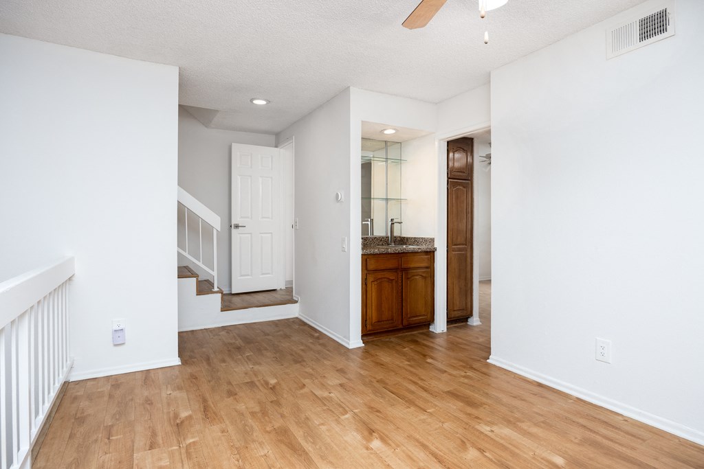 the living room and entryway of an empty house with wood floors and white walls