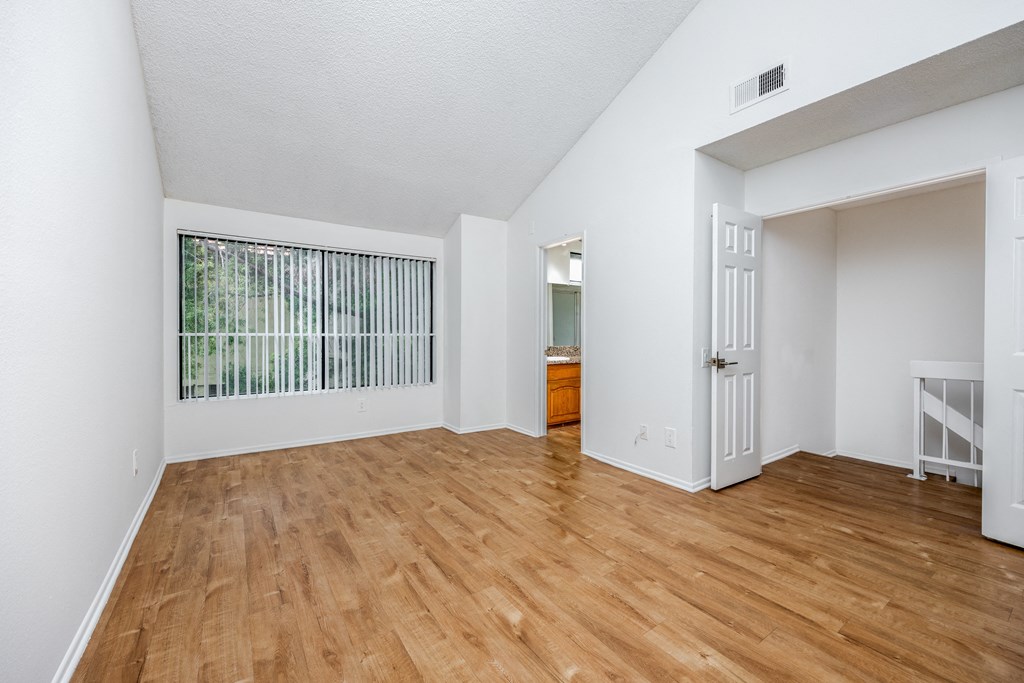 an empty living room with wood flooring and a large window