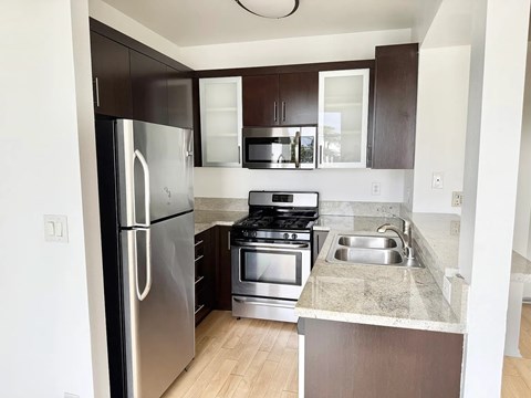 A kitchen with a stainless steel refrigerator, microwave, oven, and sink.