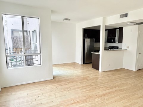 A kitchen with a refrigerator, microwave, and oven is visible through a doorway.