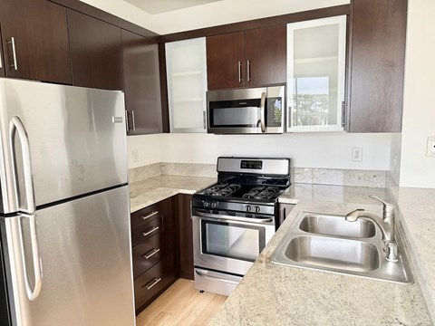 A kitchen with a stainless steel refrigerator, microwave, oven, and sink.