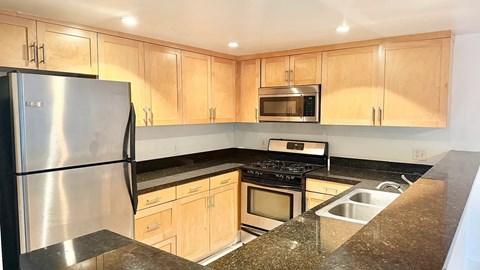 A kitchen with a stainless steel refrigerator and wooden cabinets.