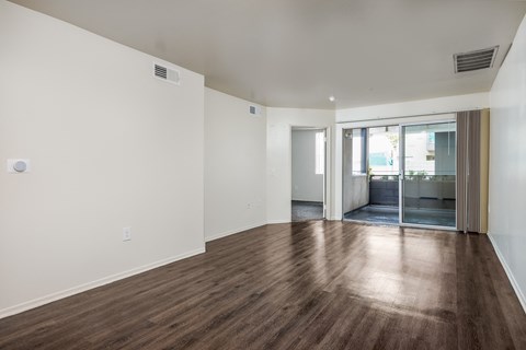 an empty living room with a hard wood floor and a glass door